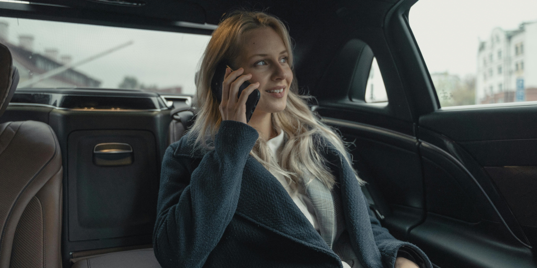 Blonde letting agent on phone in a taxi