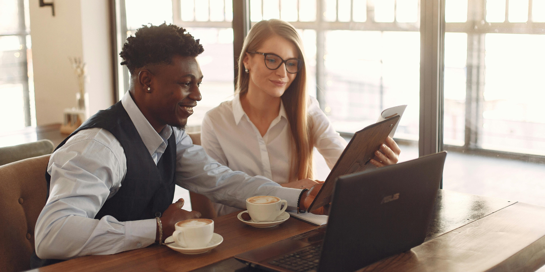 Male and female co workers in business wear working on a laptop and smiling