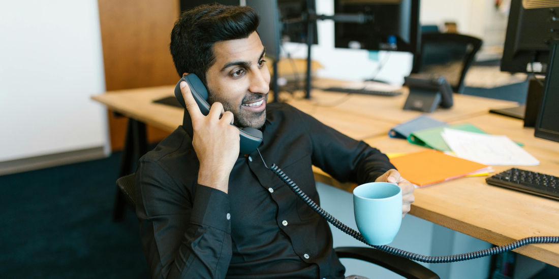 Estate agent on the phone at his desk with a coffee in hand