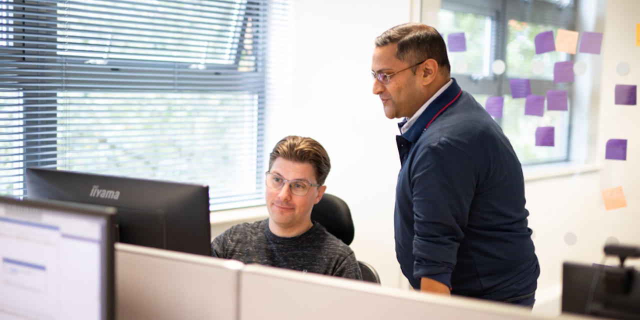 Two estate agents in the office staring at a computer