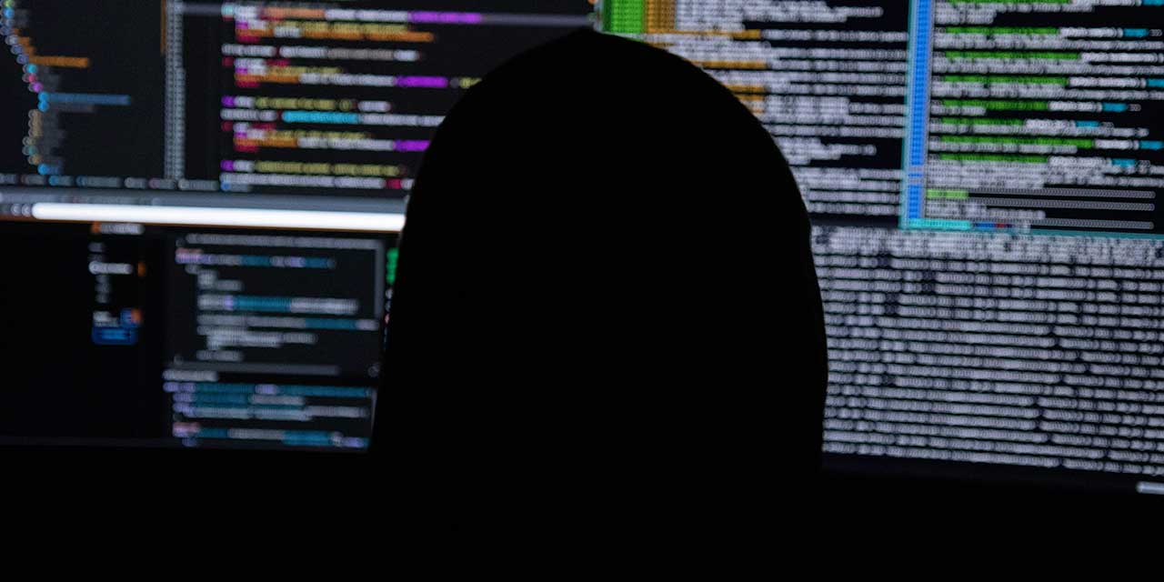 Mysterious figure sitting on a computer full of code