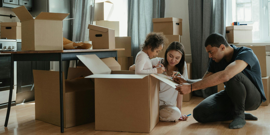 Parents with young child packing boxes to move house