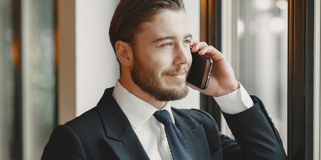 Estate agent in suit smiling while talking on phone