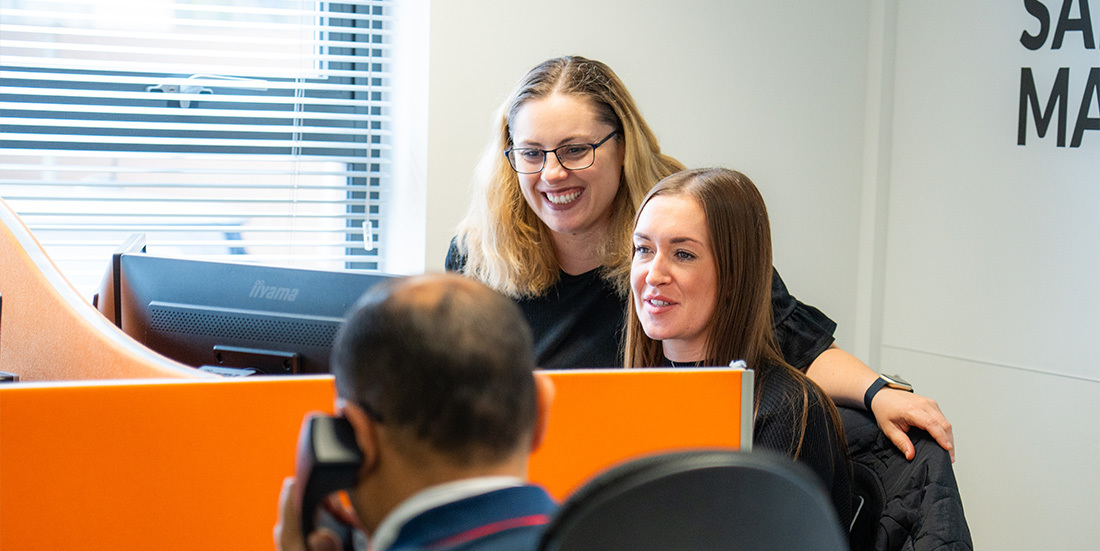 Veco team members smiling and looking at computer